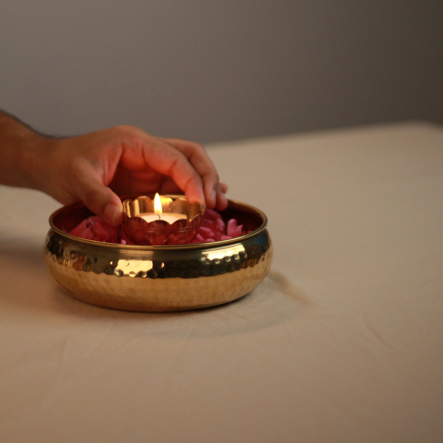 Person placing a tealight holder inside taksh decor bowl