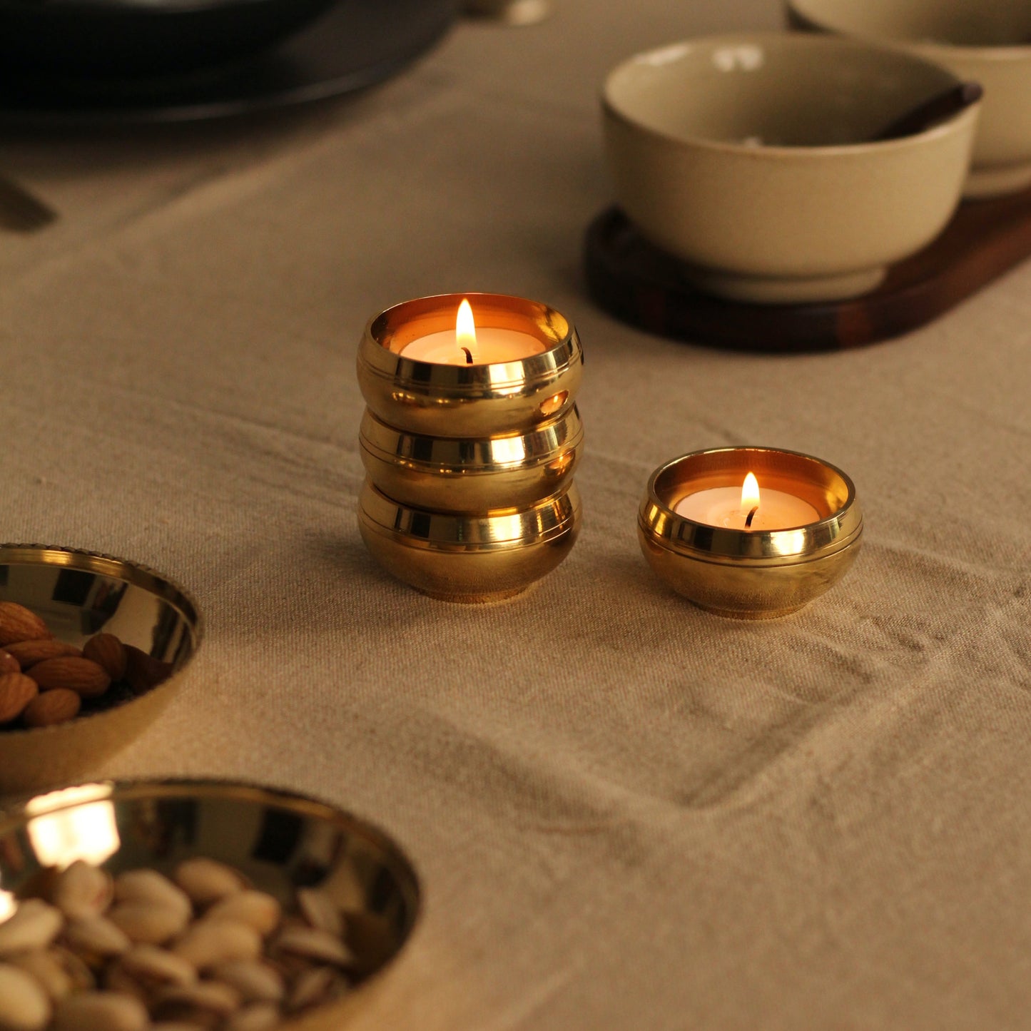 Brass tealight holders with lit candles on a textured surface