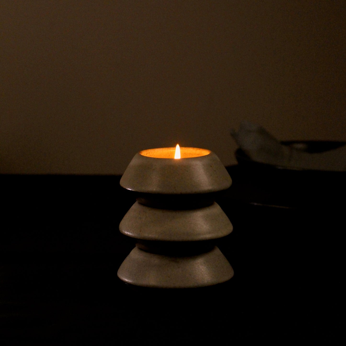 Three tealight holders stacked together showing the functional design with a candle being lit on the top most tealight holder