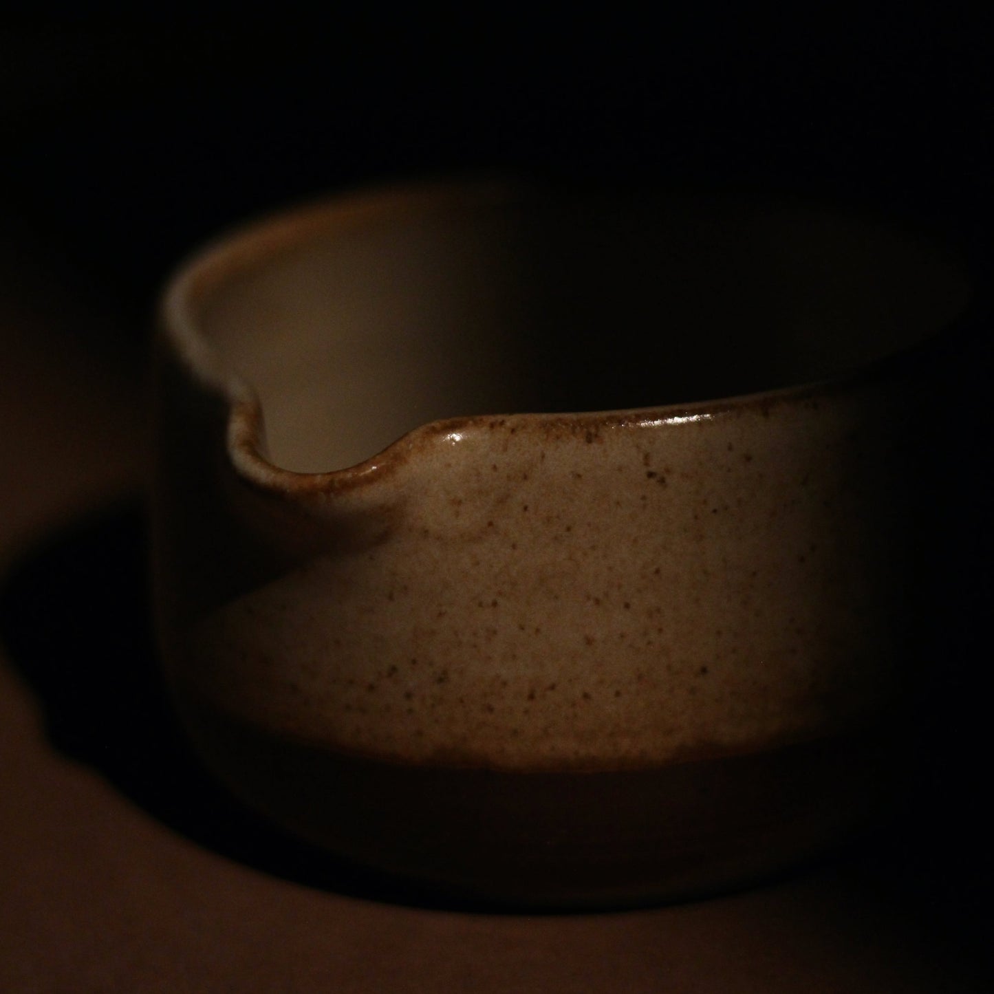 Matcha bowl with speckled brown glaze on a dark background