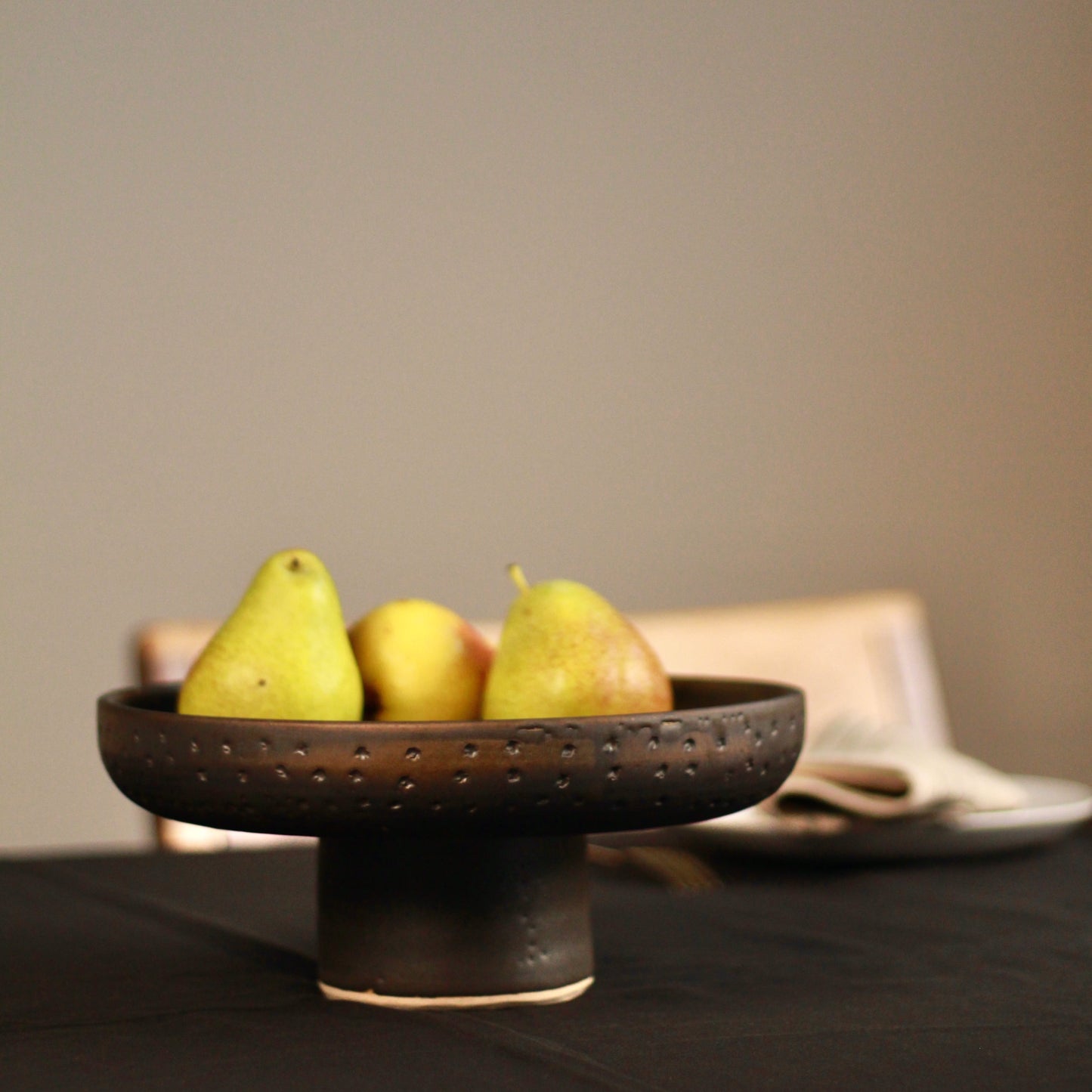 Three pears in a decorative bowl on a table