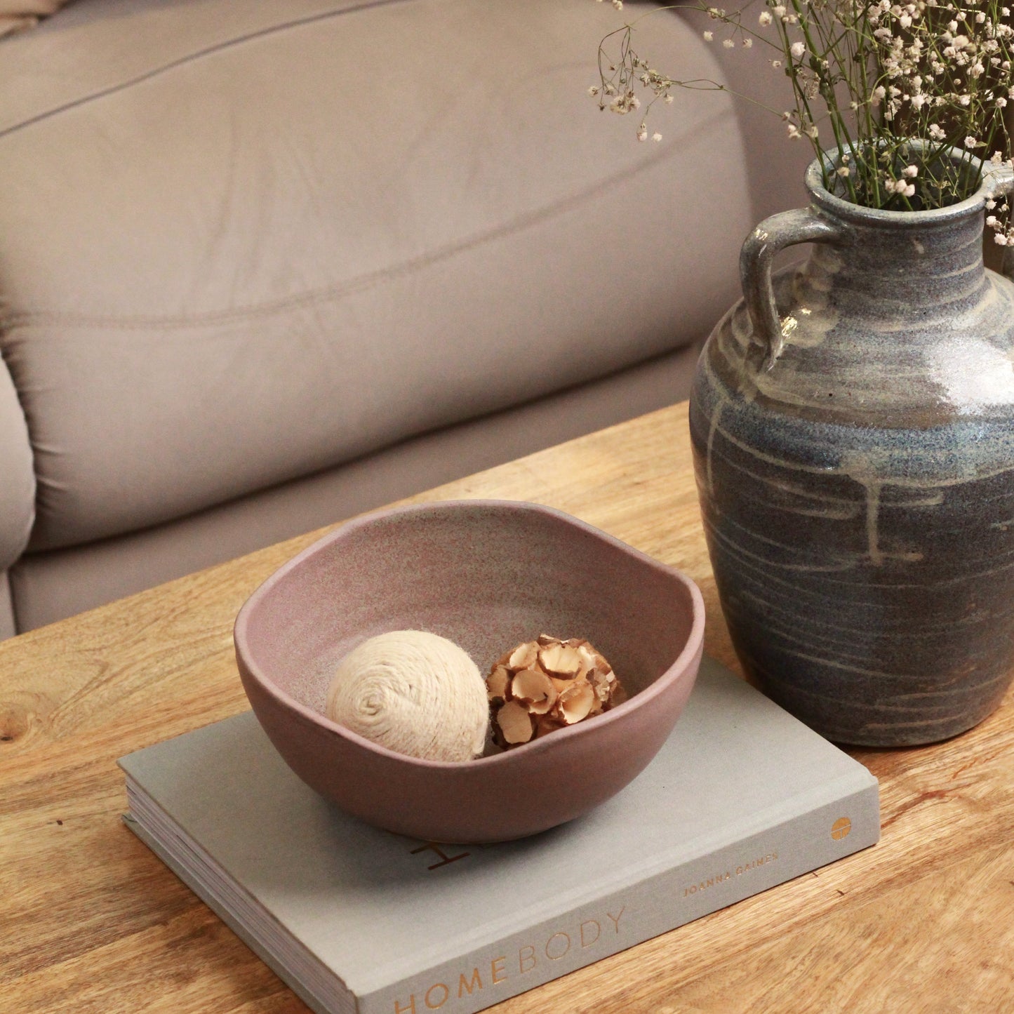 Decorative items on a wooden table with a beige sofa in the background