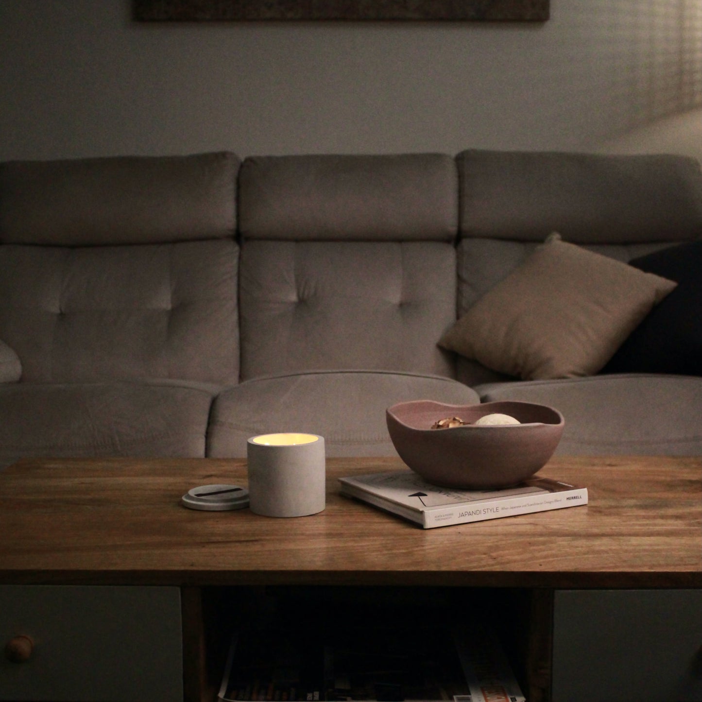 Cozy living room with a sofa, wooden coffee table, and decorative bowl with a candle placed next to it.