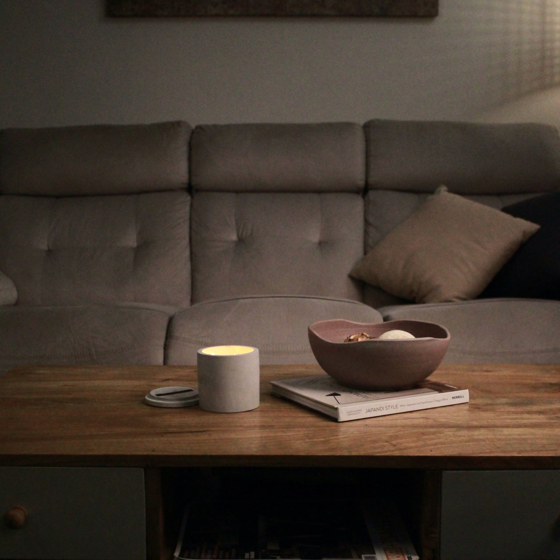 Cozy living room with a sofa, wooden coffee table, and decorative bowl with a candle placed next to it.