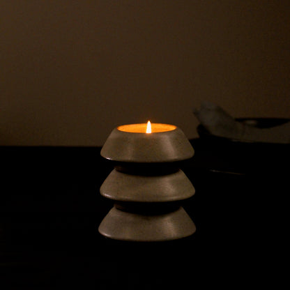Three tealight holders stacked together showing the functional design with a candle being lit on the top most tealight holder