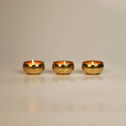 Three brass tealight holders on a beige background