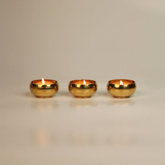 Three brass tealight holders on a beige background