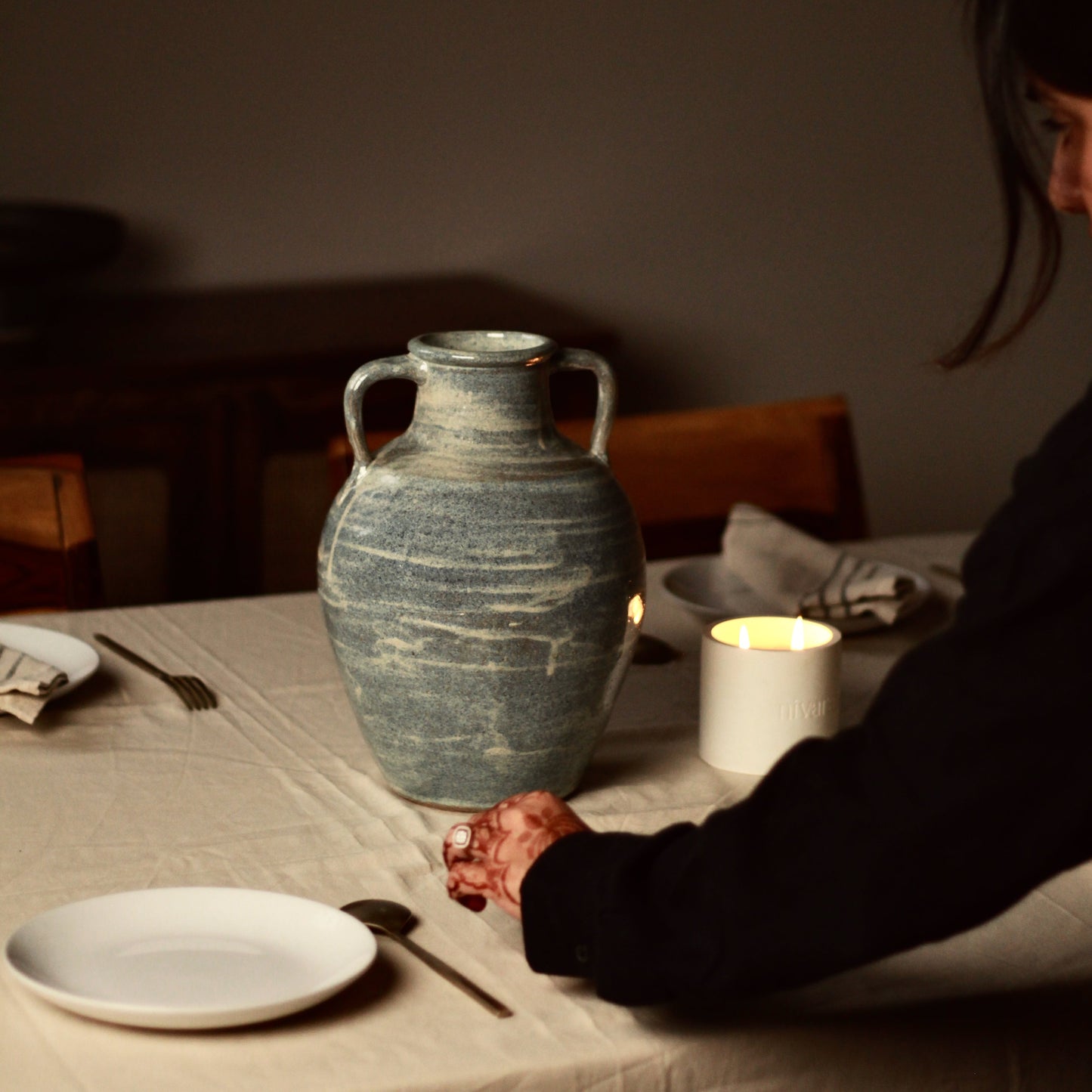 Person setting up a table with a large blue samudra ceramic vase