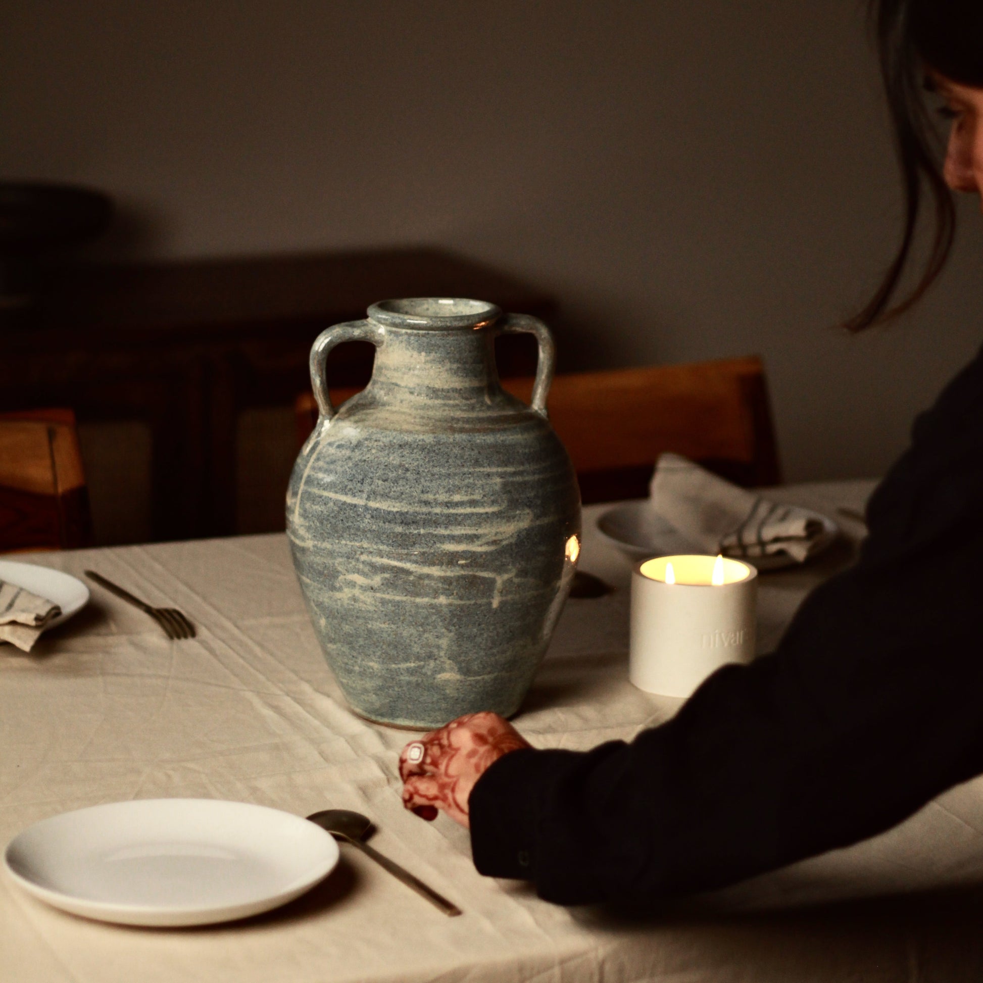 Person setting up a table with a large blue samudra ceramic vase