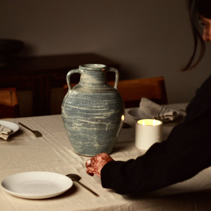 Person setting up a table with a large blue samudra ceramic vase