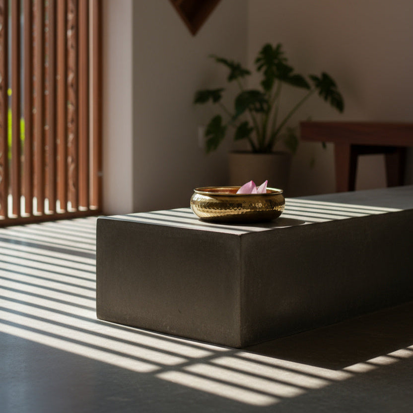 Taksh bowl with lotus on a stone surface, sunlit room with plants and wooden elements.